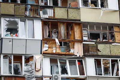 a-residents-stands-on-a-balcony-of-his-apartment-damaged-during-russian-missile-and-drone-strikes-am.webp