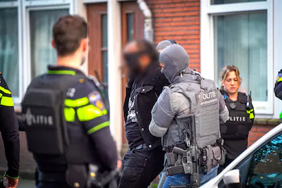 de-aangehouden-verdachte-werd-gemaskerd-naar-buiten-gebracht.webp