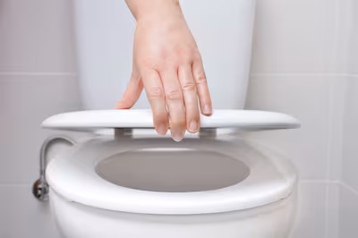 hand-of-a-woman-closing-the-lid-of-a-toilet.avif