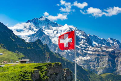 swiss-flag-waving-and-tourists-admire-the-peaks-of-jungfrau-mountain-on-a-mannlichen-viewpoint-berne.webp