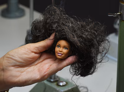 a-designer-adds-hair-to-a-barbie-doll-prototype-at-a-workshop-in-the-mattel-design-center-as-the-ico.avif