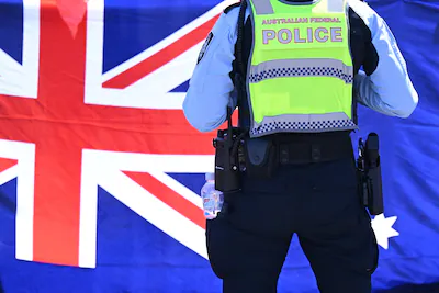 epa12545097-a-police-officer-stands-in-front-of-an-australian-flag-ahead-of-the-arrival-of-zhao-leji.webp