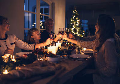 family-toasting-with-wine-in-a-christmas-dinner-at-home-in-the-living-room-happy-family-celebrating.avif