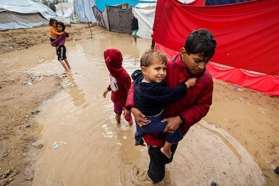 palestinian-children-walk-in-flood-water-after-heavy-rain-at-a-makeshift-camp-housing-displaced-pale.jpeg