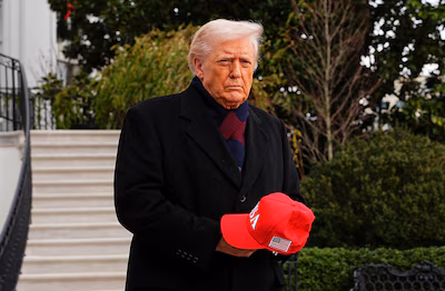 u-s-president-donald-trump-holds-a-red-cap-before-departing-for-the-army-navy-football-game-in-balti.avif