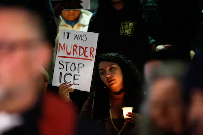 a-demonstrator-holds-a-sign-during-a-candlelight-vigil-during-a-protest-in-response-to-the-fatal-sho.webp
