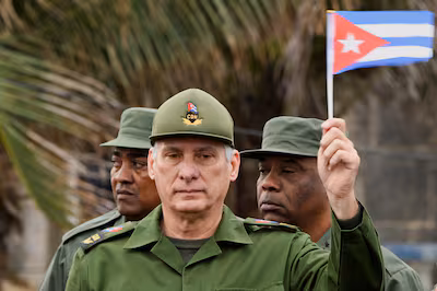 cuba-s-president-miguel-diaz-canel-waves-a-cuban-flag-during-a-march-outside-the-u-s-embassy-to-prot.avif