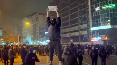 in-this-frame-grab-from-video-obtained-by-the-ap-outside-iran-a-masked-demonstrator-holds-a-picture.avif