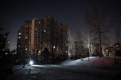 people-use-flashlights-to-light-their-way-on-an-unpowered-street-in-the-troieshchyna-residential-are.webp