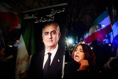 a-participant-walks-with-a-portrait-of-the-son-of-the-last-shah-of-iran-reza-pahlavi-in-protest-agai.webp