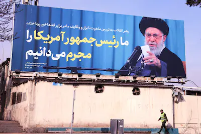 an-iranian-soldier-walk-past-a-billboard-carrying-the-image-of-iran-s-supreme-leader-ayatollah-ali-k.webp