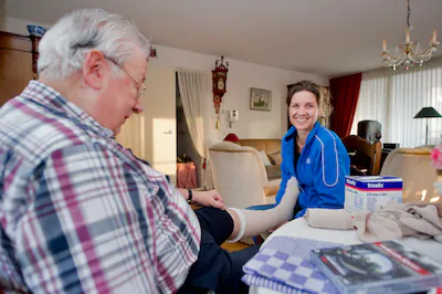 wijkverpleegkundige-madelon-van-tilburg-met-client-meneer-hop-buurtzorg-nederland-foto-marco-de-swar.webp